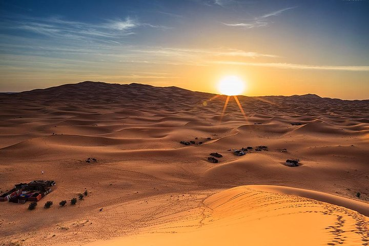 Witness the serene beauty of the Lahbab desert as the sun rises casting golden hues over endless dunes perfect for camel rides and exciting dune bashing adventures.